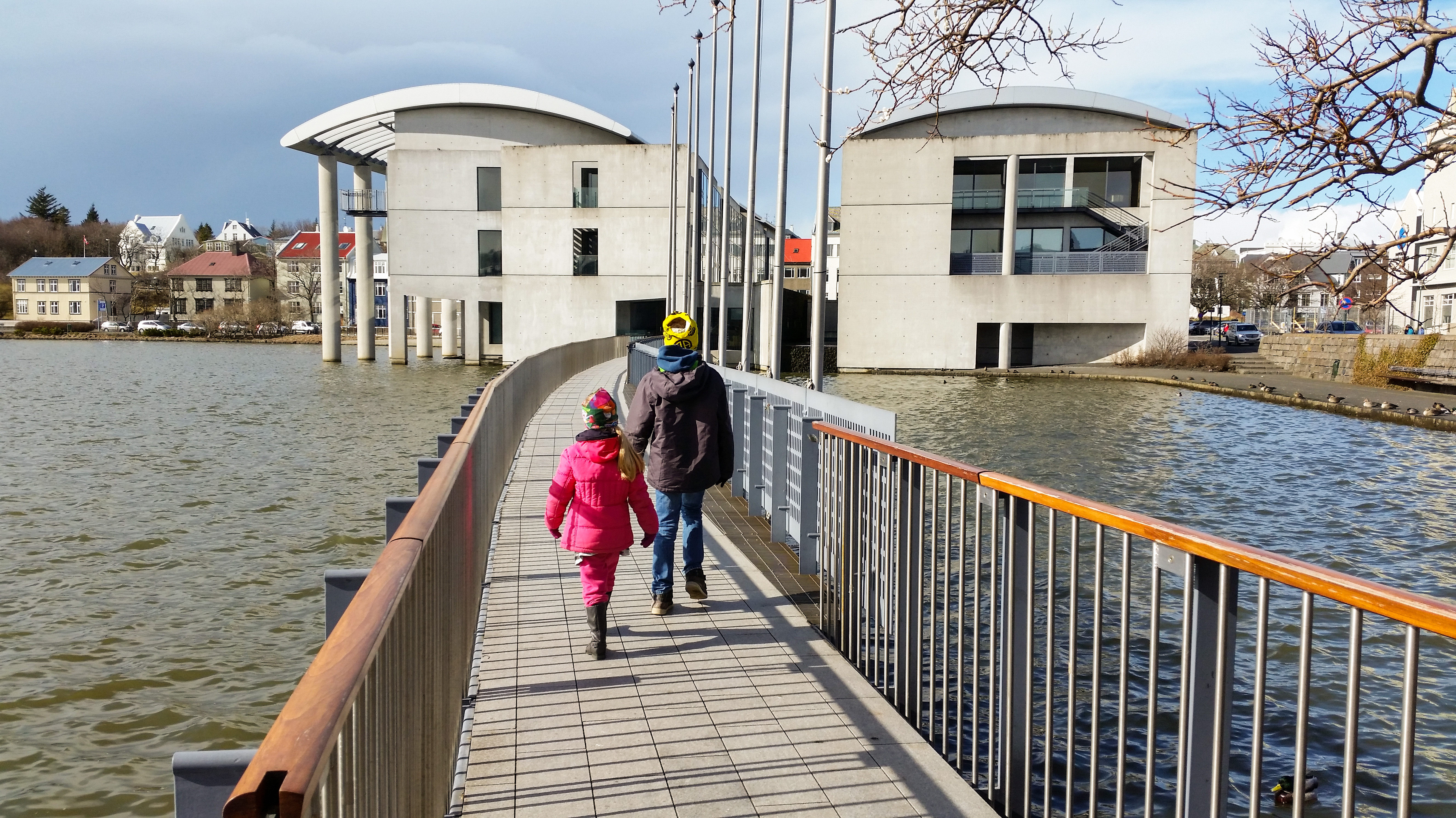 Kinder laufen über eine Brücke des Tjörnin Stadtteiches zum Rathaus