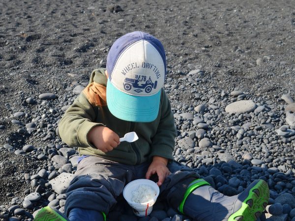 Kind macht Picknick am Steinstrand