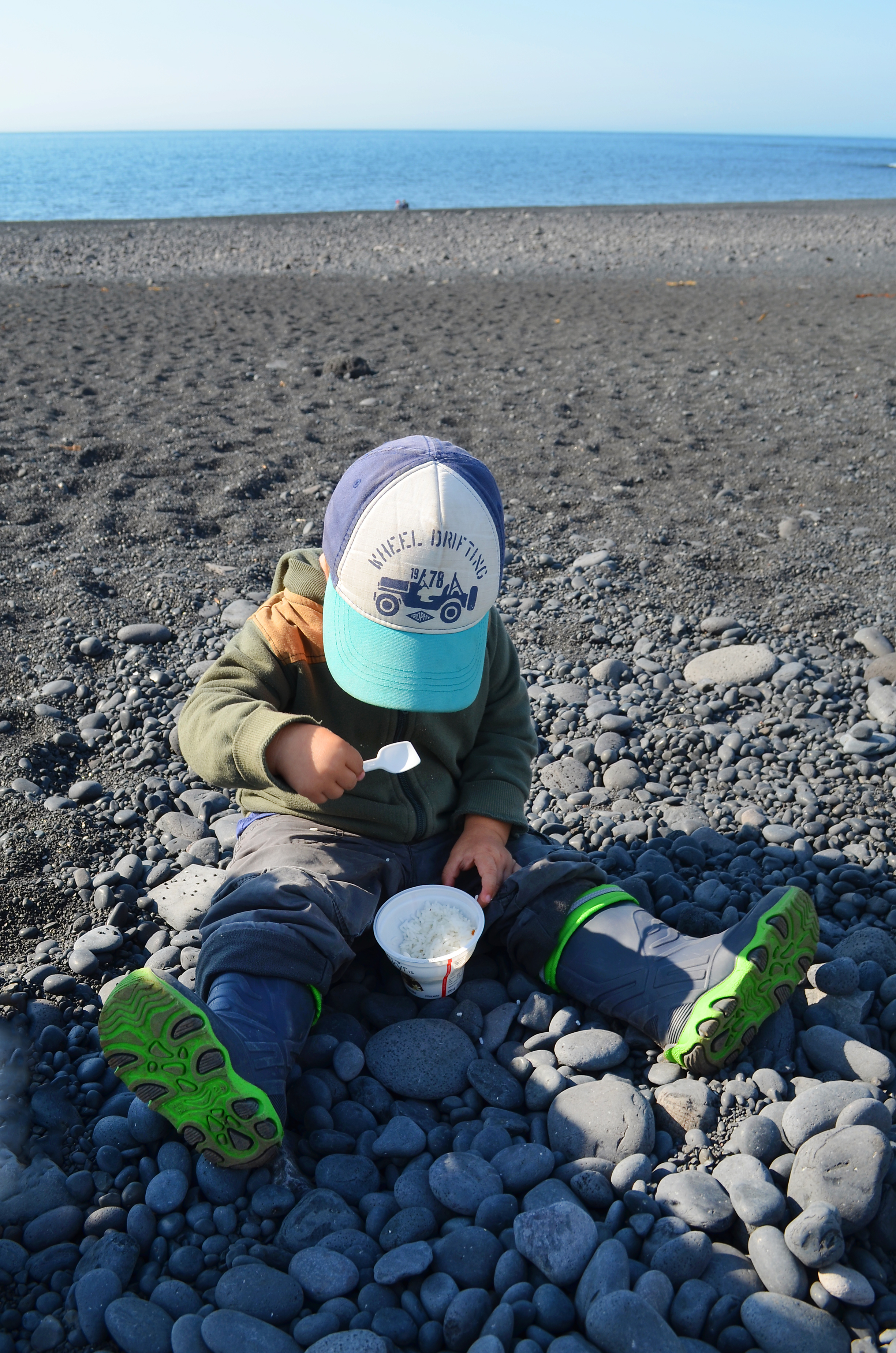 Kind macht Picknick am Steinstrand