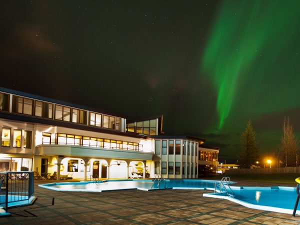 Nordlichter am Himmel und Aussenansicht des Hotel Örk in Südisland