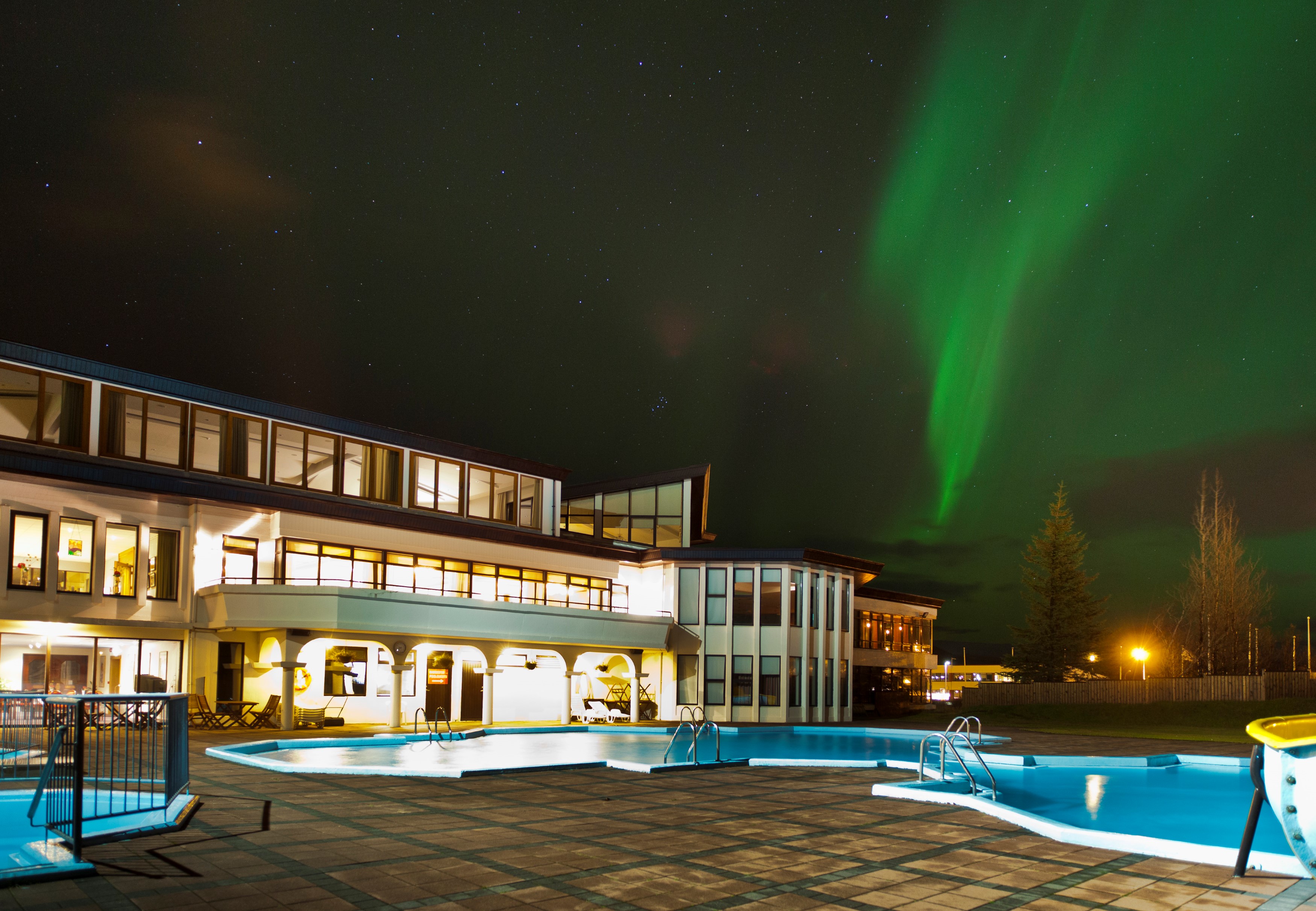 Nordlichter am Himmel und Aussenansicht des Hotel Örk in Südisland