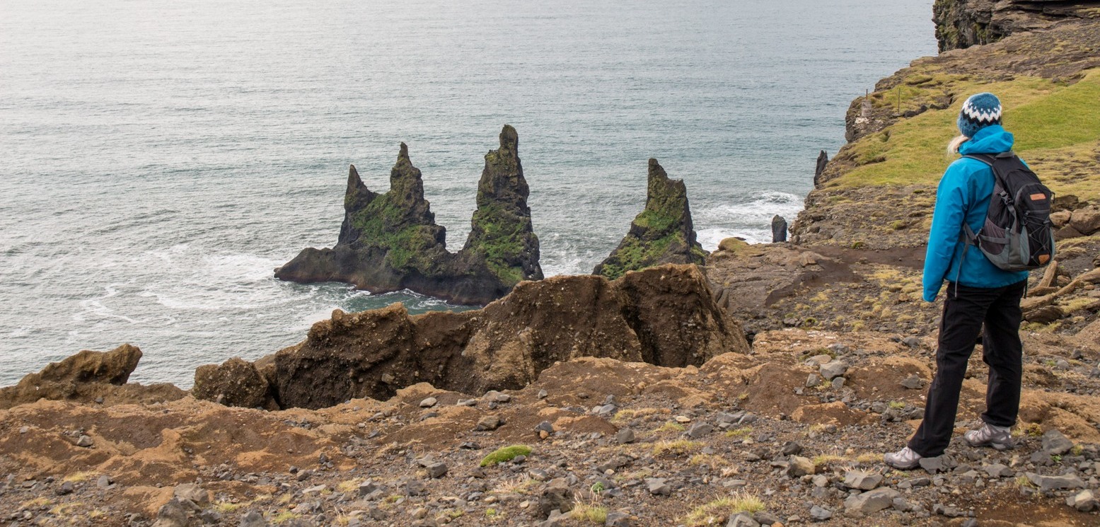 Wilde Küstenlandschaft mit Felsen im Meer, Reisende schaut auf das Meer