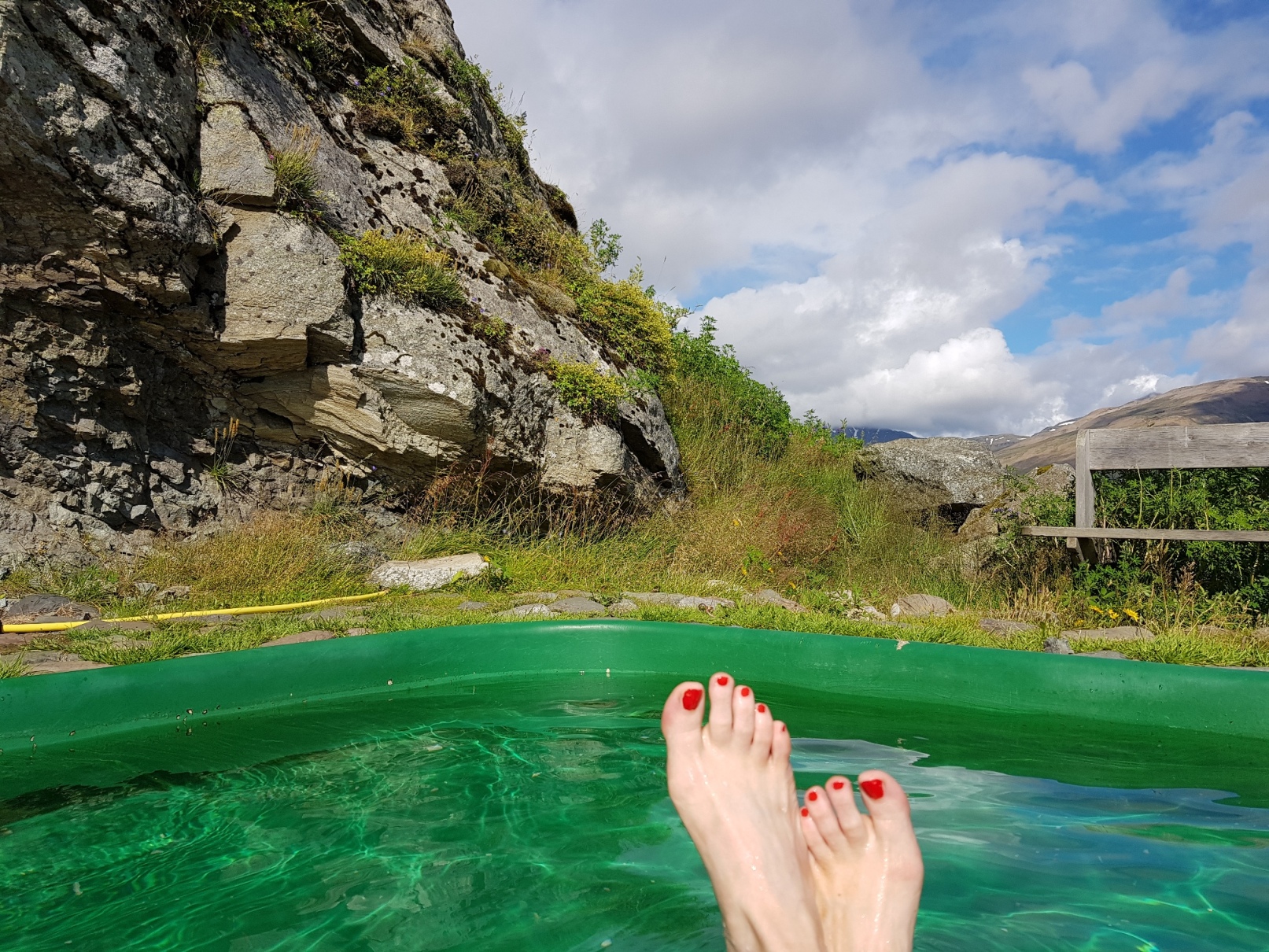 Füße schauen aus einem Hot Pot heraus in Südostisland