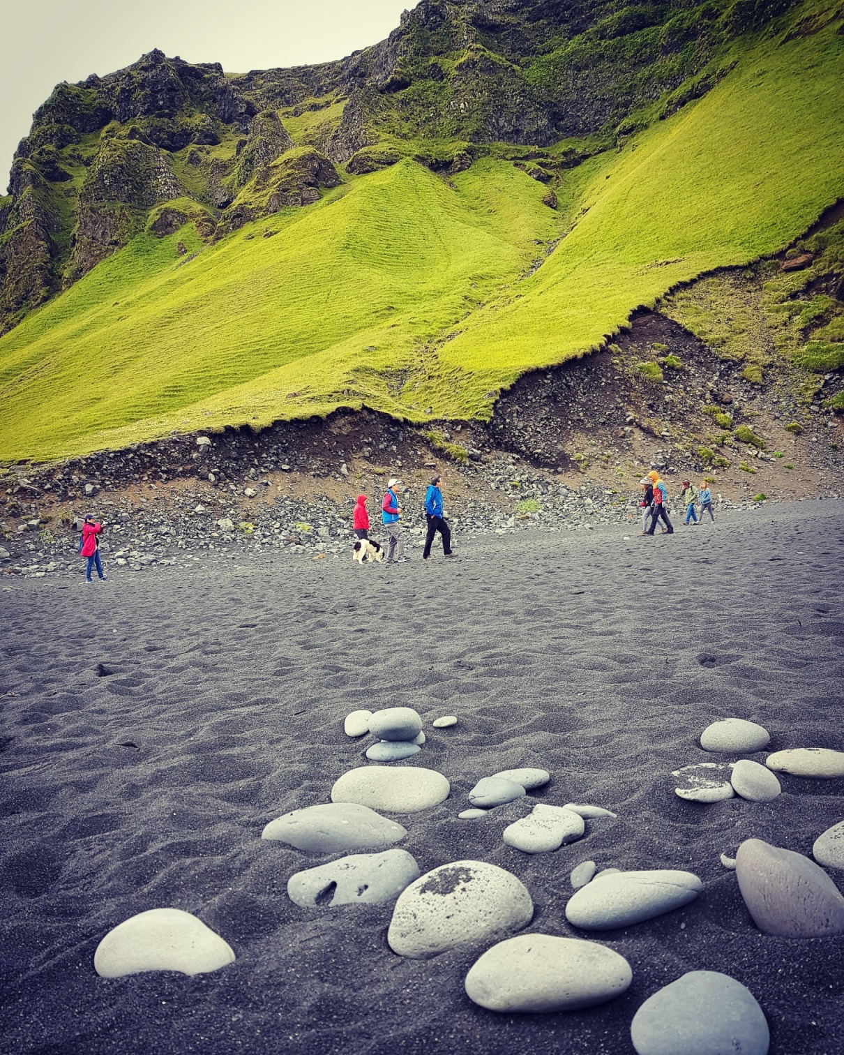 Wanderer am Strand bei Südisland, Moosbewachsene Felsen im Hintergrund