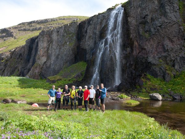 Wandergruppe posiert vor einem Wasserfall in Island